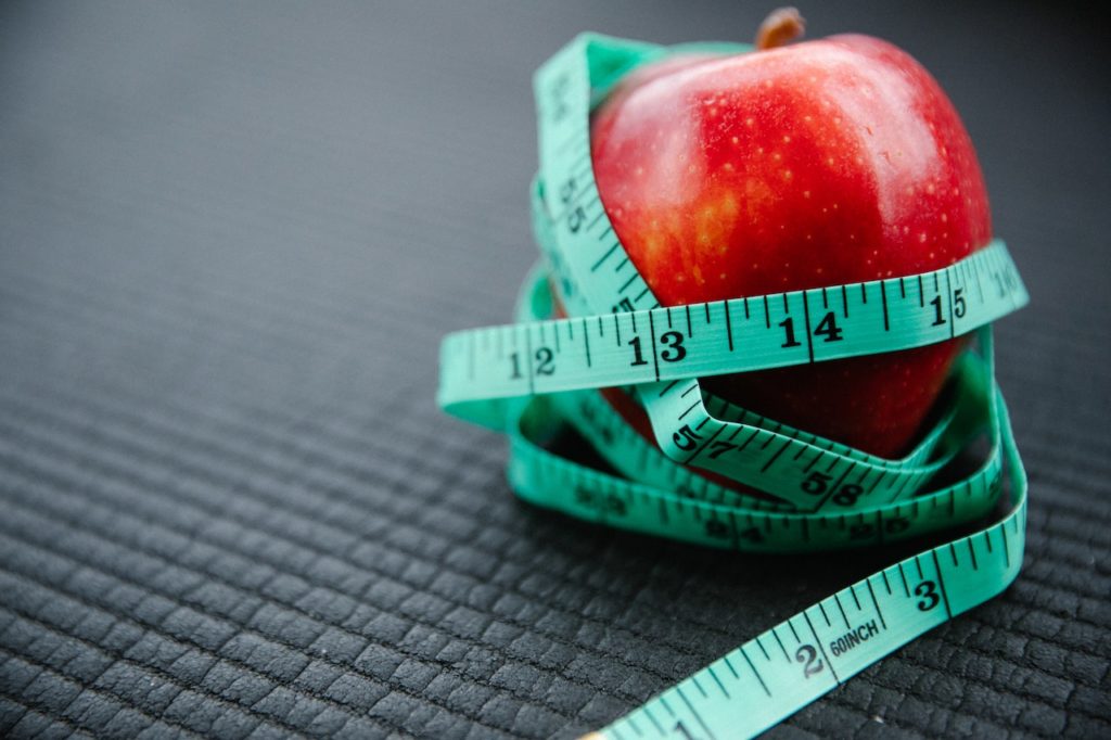 Une pomme entourée d'un mètre ruban qui représente une alimentation saine pour maigrir et avoir un ventre plat. 