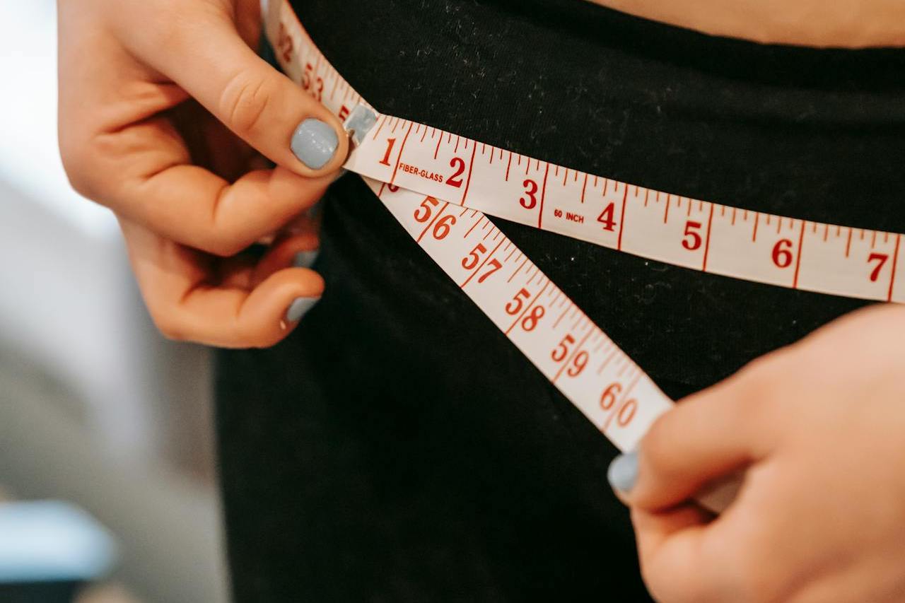 Jeune femme faisant son tour de taille avec un mètre ruban.