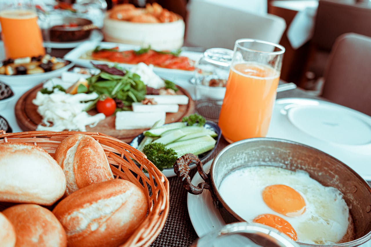 Une table de petit-déjeuner avec des oeufs, des légumes, du jus, du pain...